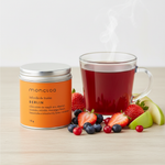 Mini lata Chá Berlin Moncloa ao lado de xícara com chá quente de frutas vermelhas