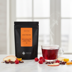 Pouch Chá Good Feelings Moncloa ao lado de xícara com chá quente de frutas e framboesa